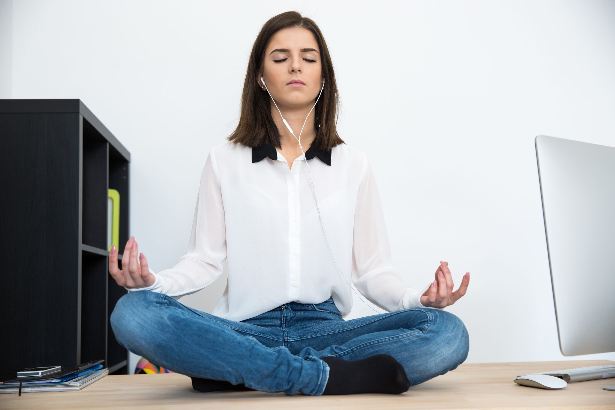 Young woman meditating at the table in office